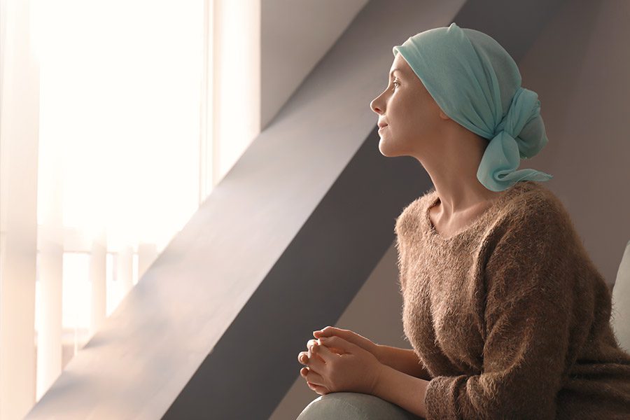 Critical Illness Insurance - A Woman with Cancer Sitting and Looking Out a Hospital Window