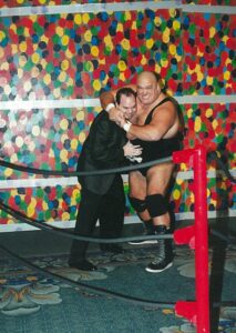 Bob Donohue in a wrestling ring being put in a headlock by a professional wrestler.