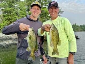 Brendan Dooley and Chris Dooley holding two small mouth bass they caught on Eagle Lake in Canada.