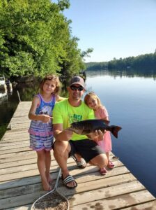 Jason Phillips holding a large mouth bass he caught with his two daughters on Lake Eau Claire.