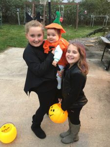 Curtis' three kids dressed up for Halloween as witches and a pumpkin.