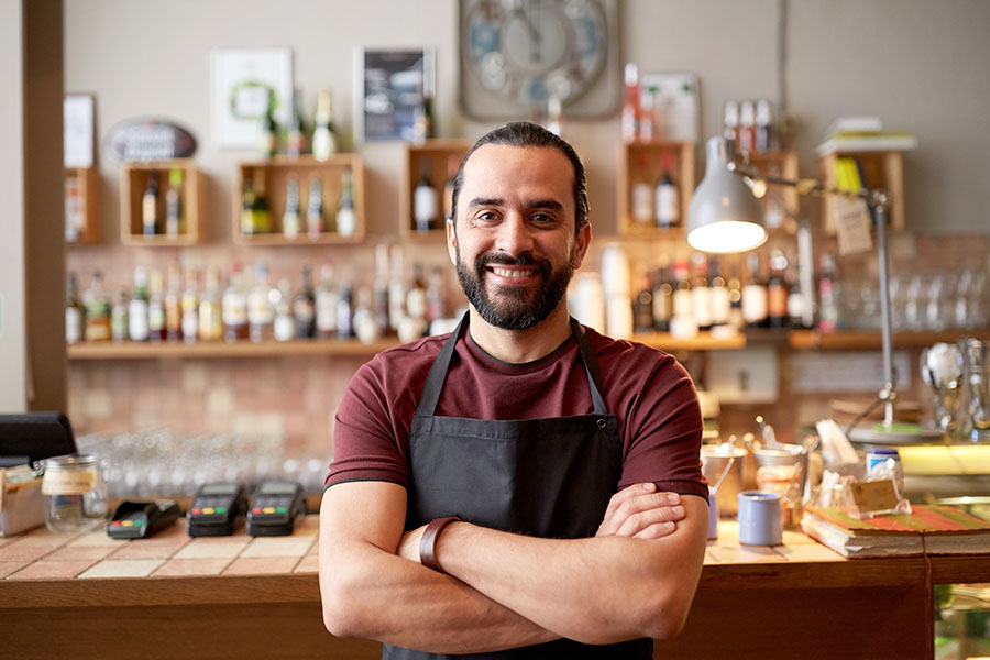 Business Insurance - Portrait of a Cheerful Young Small Business Man Standing in His Shop with His Arms Folded