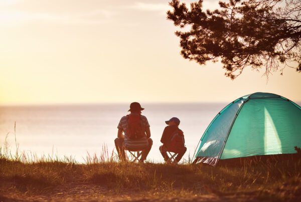 Rear view of father and son camping looking over Lake Superior in northern Wisconsin as the sun is setting..