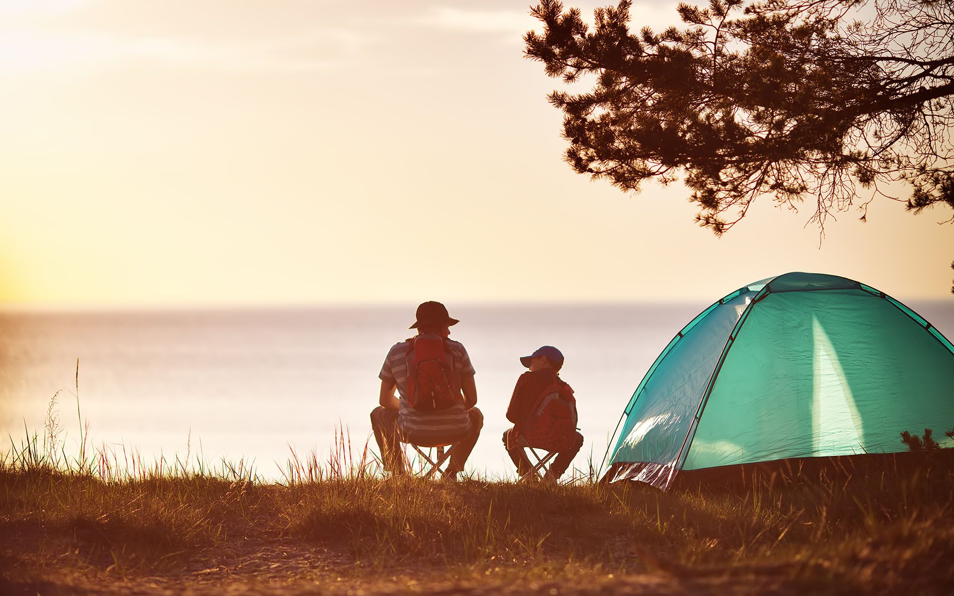 Rear view of father and son camping looking over Lake Superior in northern Wisconsin as the sun is setting..