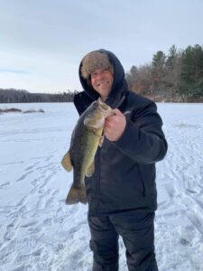 Kyle Yudes ice fishing holding a bass in his hand