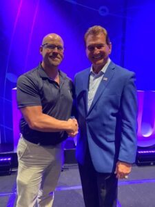 Kyle Yudes shaking hands with Joe Theismann at a conference