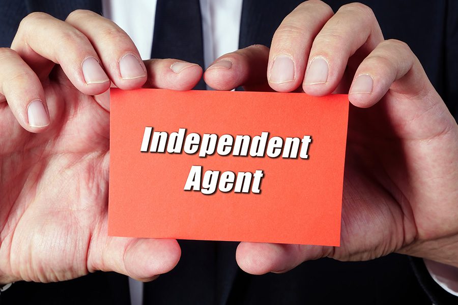 close up of a man in a suit holding a red business card that reads independent agent