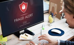 Close-up of a man placing a fraud alert on his desktop computer.