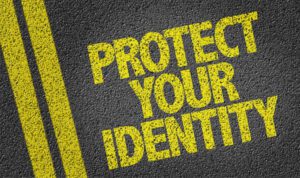Protect Your Identity written in yellow paint on a paved road.