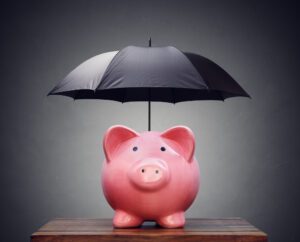 Pink piggy bank covered by a black umbrella mimicking how commercial umbrella insurance protects a business's finances.