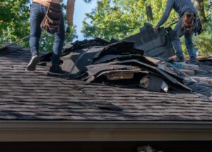 Two men fixing a roof after extreme hail storm tore it up.