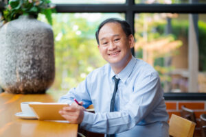 Smiling middle-aged Asian independent insurance agent specializing in auto and homeowners insurance.