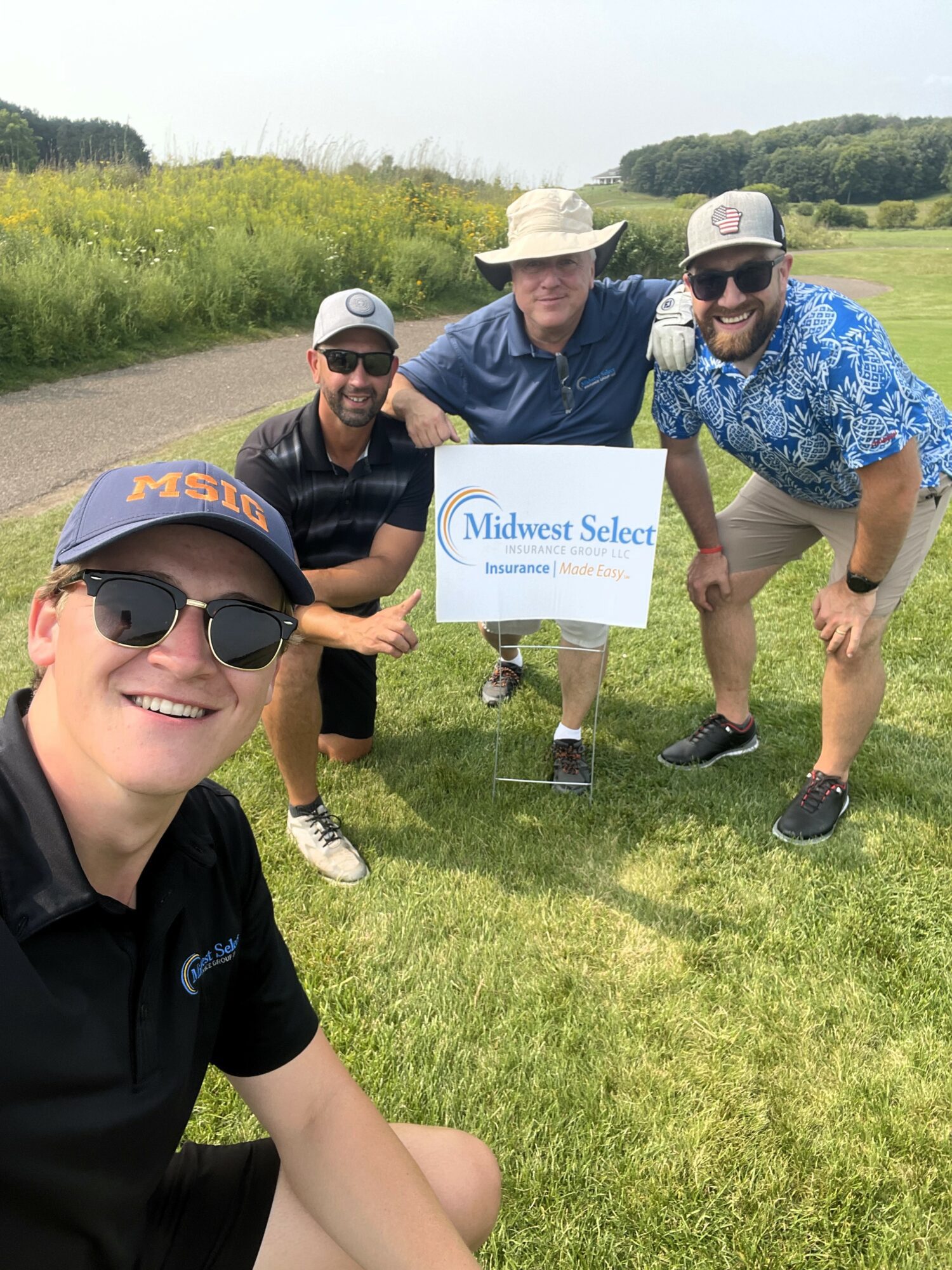 Midwest Select Insurance Group Insurance Agents Brendan Dooley, Jason Phillips, Mario Racanelli, and Curtis Deprey in front of MSIG sponsorship sign.