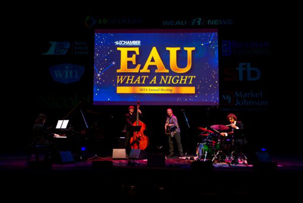 A band playing under the blue and purple lights of the Pablo Center at the Eau Claire Chamber of Commerce's 2024 Annual Meeting, "Eau What A Night."