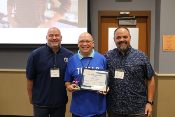 Wally Wheeler holding the Mover & Shaker Award for Leadership Eau Claire Class of 2024 standing next to Phil Swiler of VSA and Michael Strubel of WEAU 13 News.
